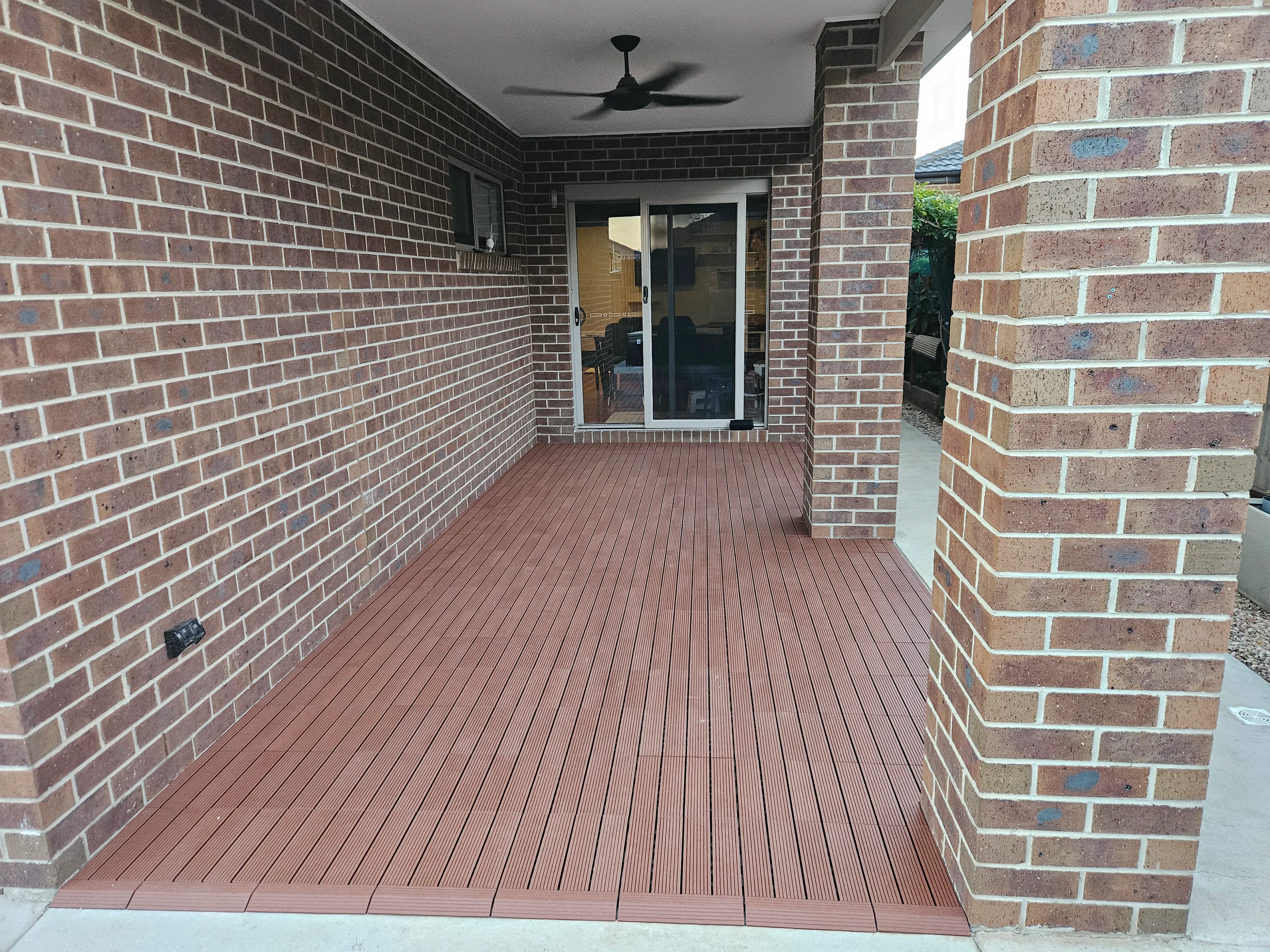 Interlocking composite deck tiles laid over an alfresco slab